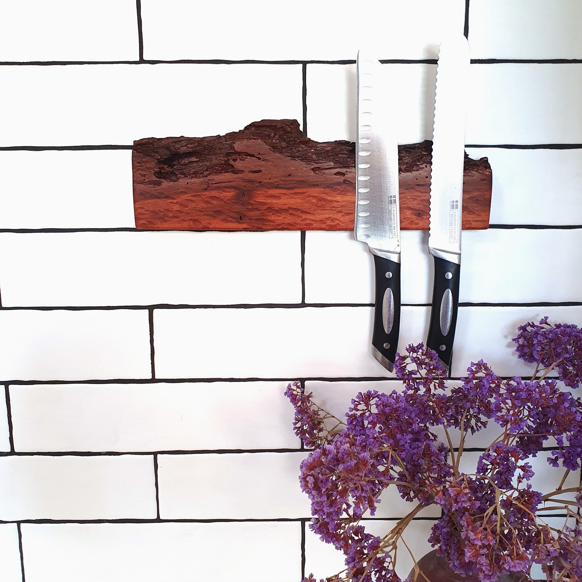 Wooden cutting board with knives on a white brick wall background