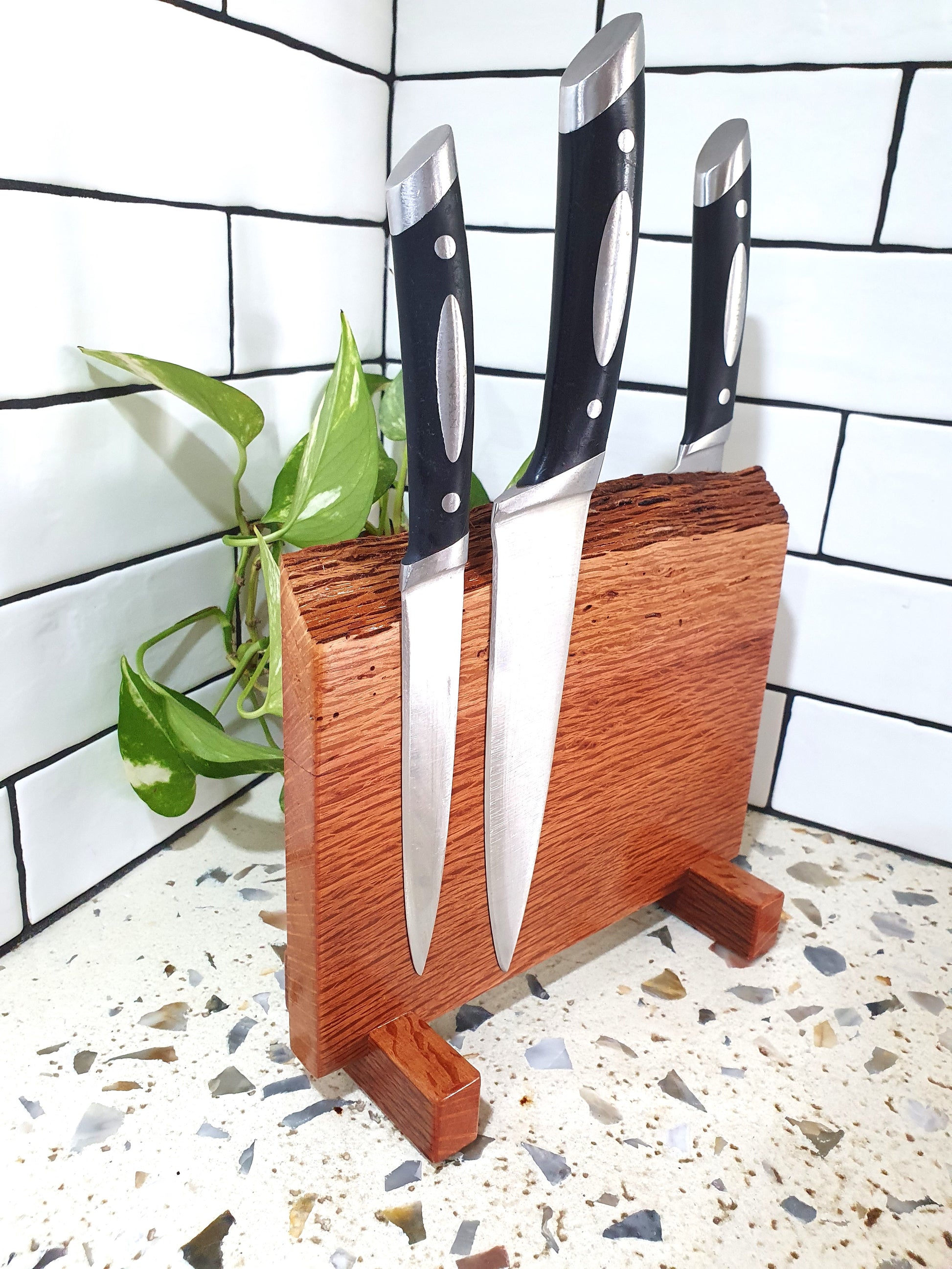 Set of knives in a wooden block against a tiled wall background