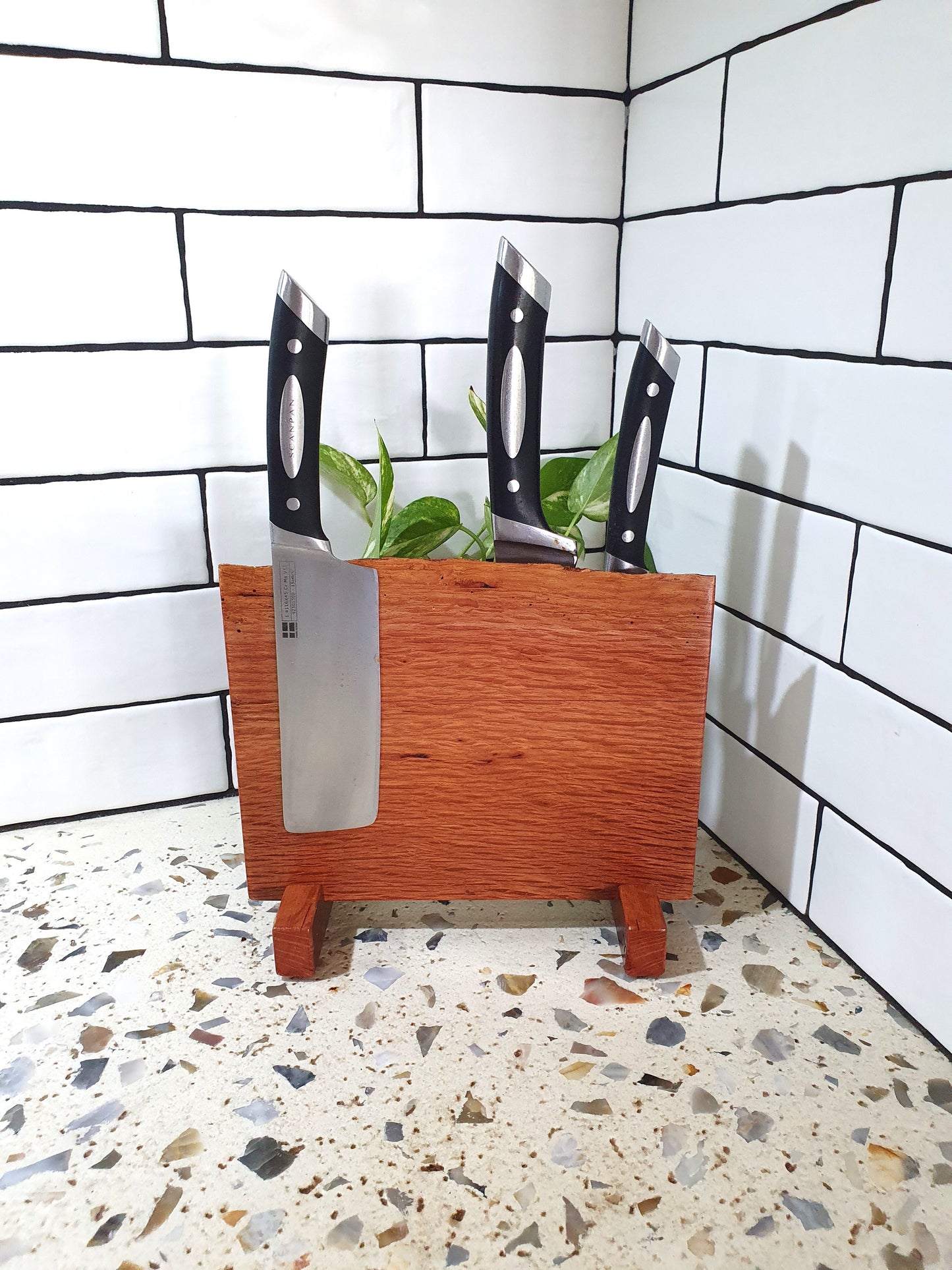Wooden knife block with knives against a tiled wall.
