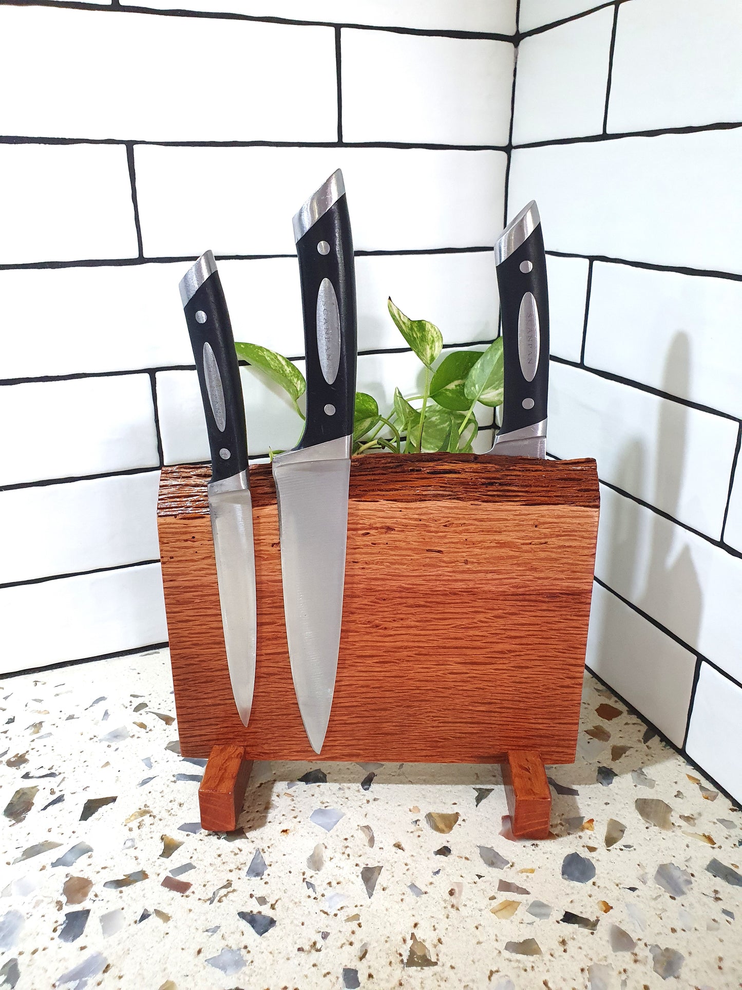 Wooden knife block with three knives on a tiled floor