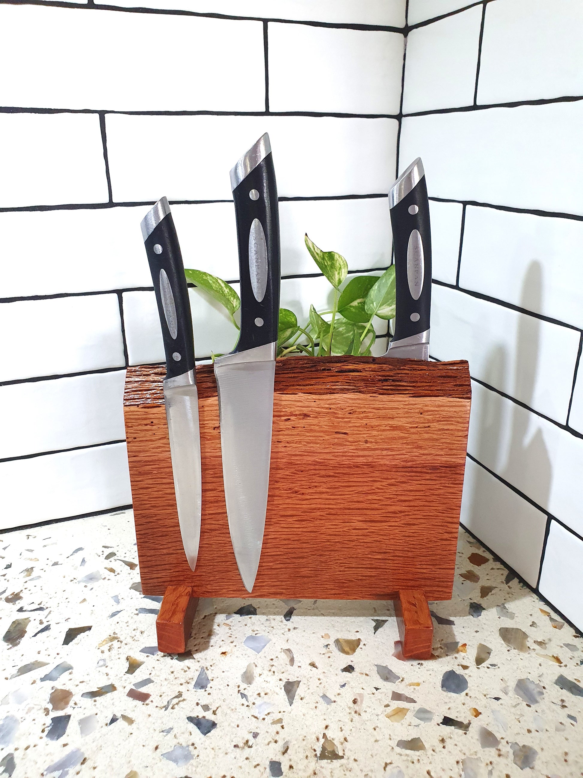 Wooden knife block with three knives on a tiled floor