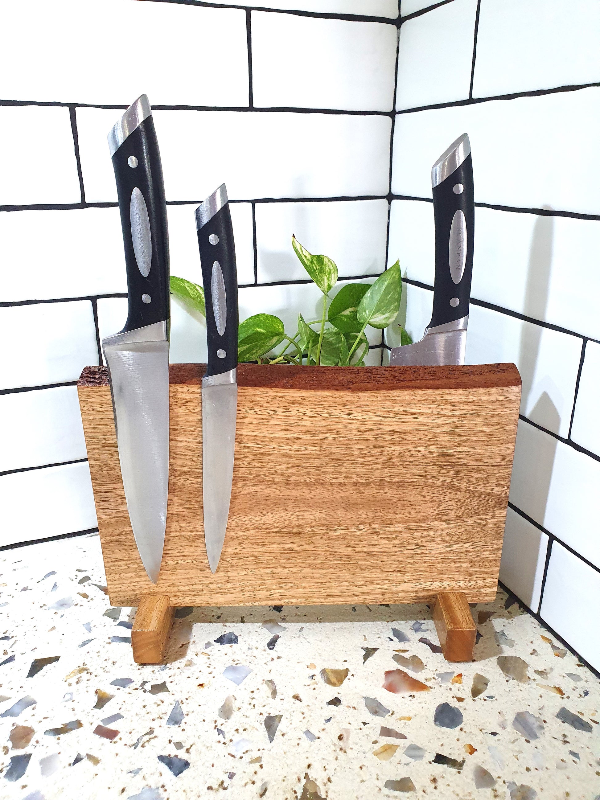Wooden knife block with three knives on a tiled floor