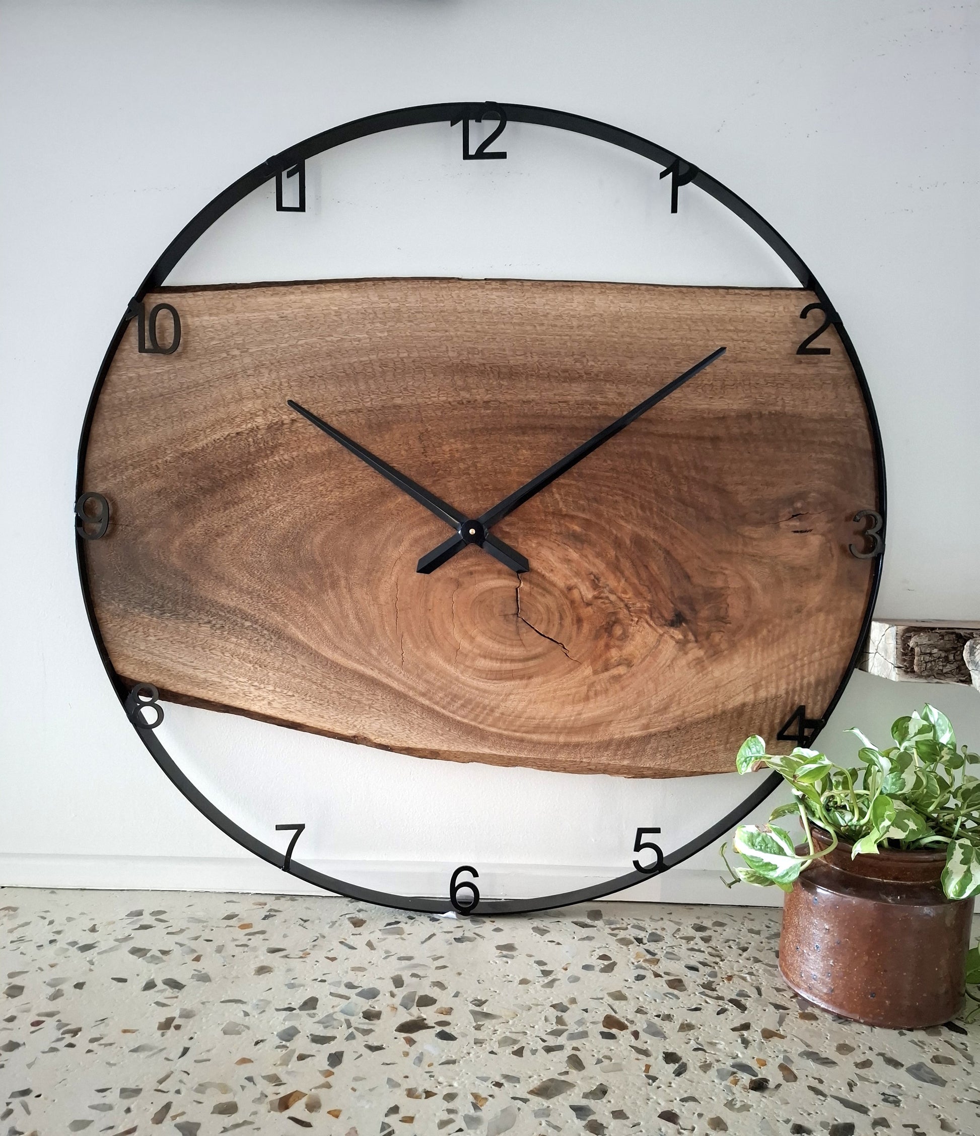 Wooden wall clock with black frame on a white wall
