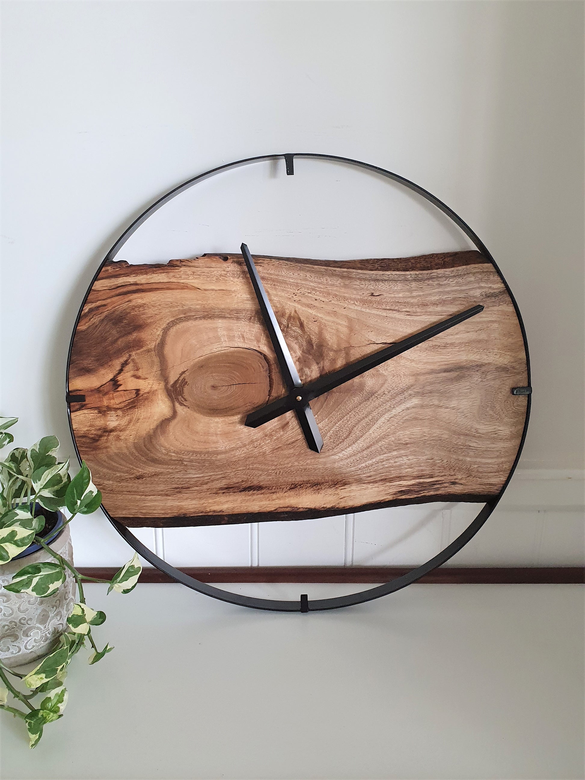 Wooden wall clock with black metal frame on a white wall