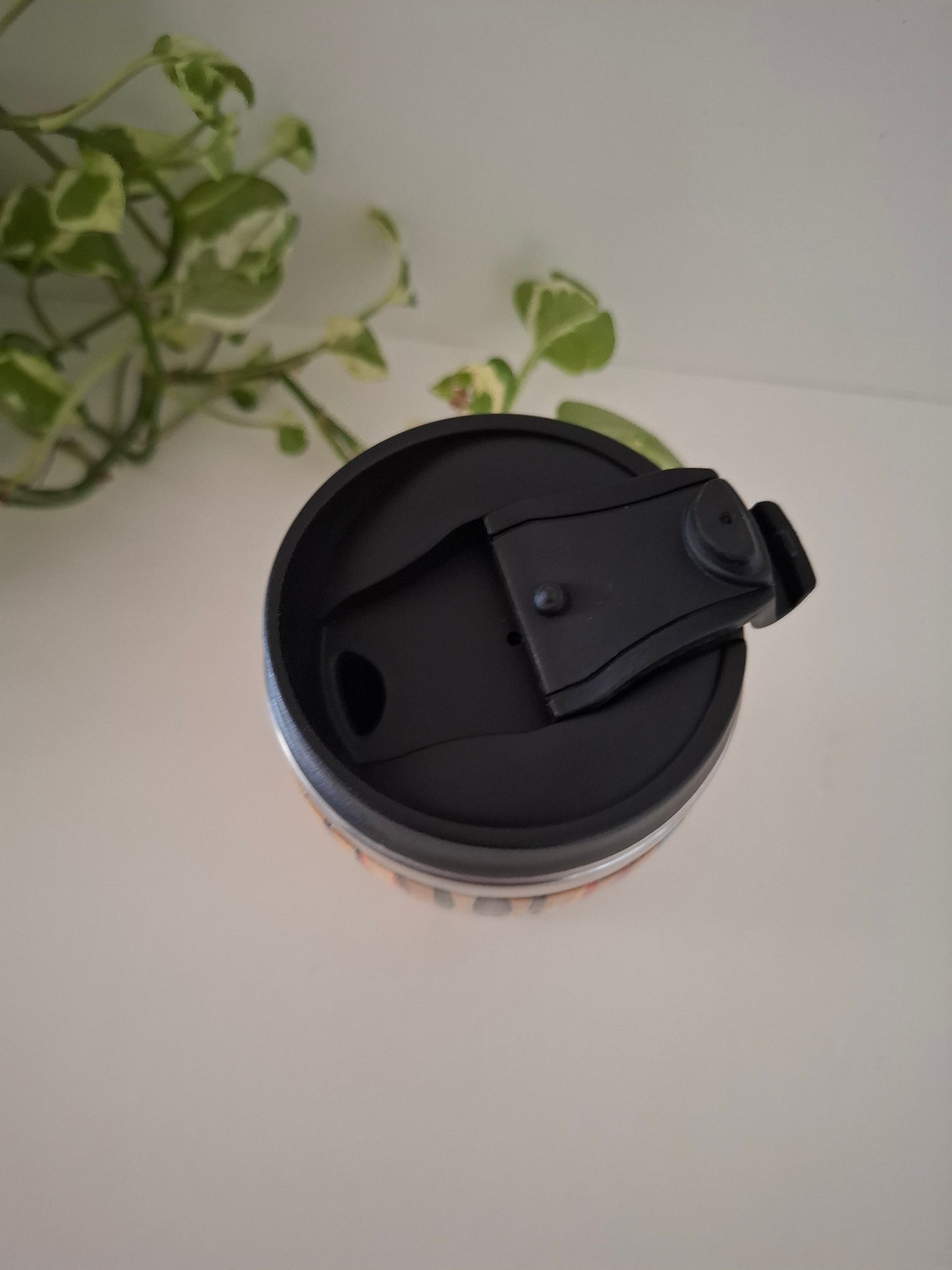 Black lid on a cup with a plant in the background