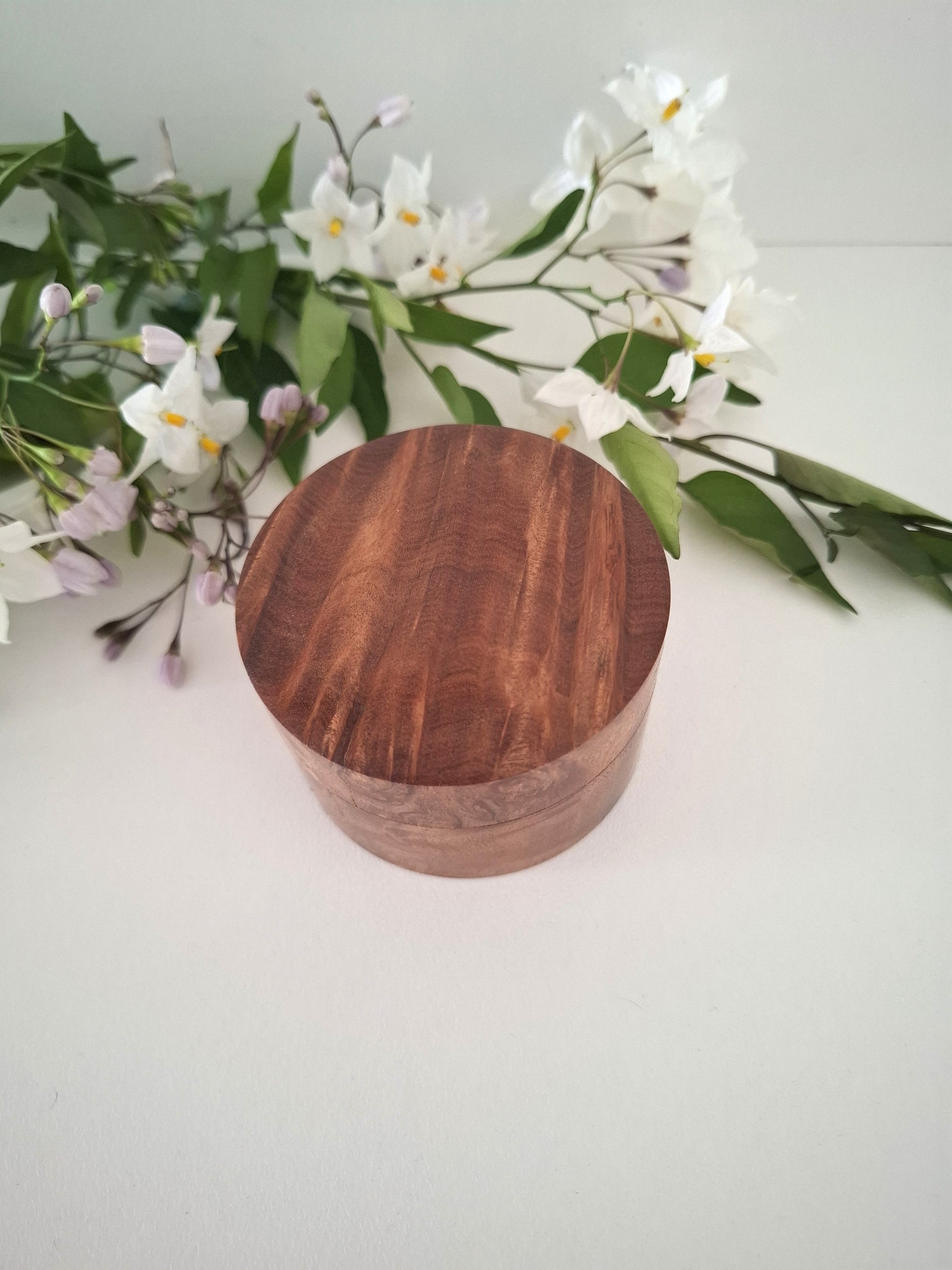 Wooden container with a floral arrangement on a light background