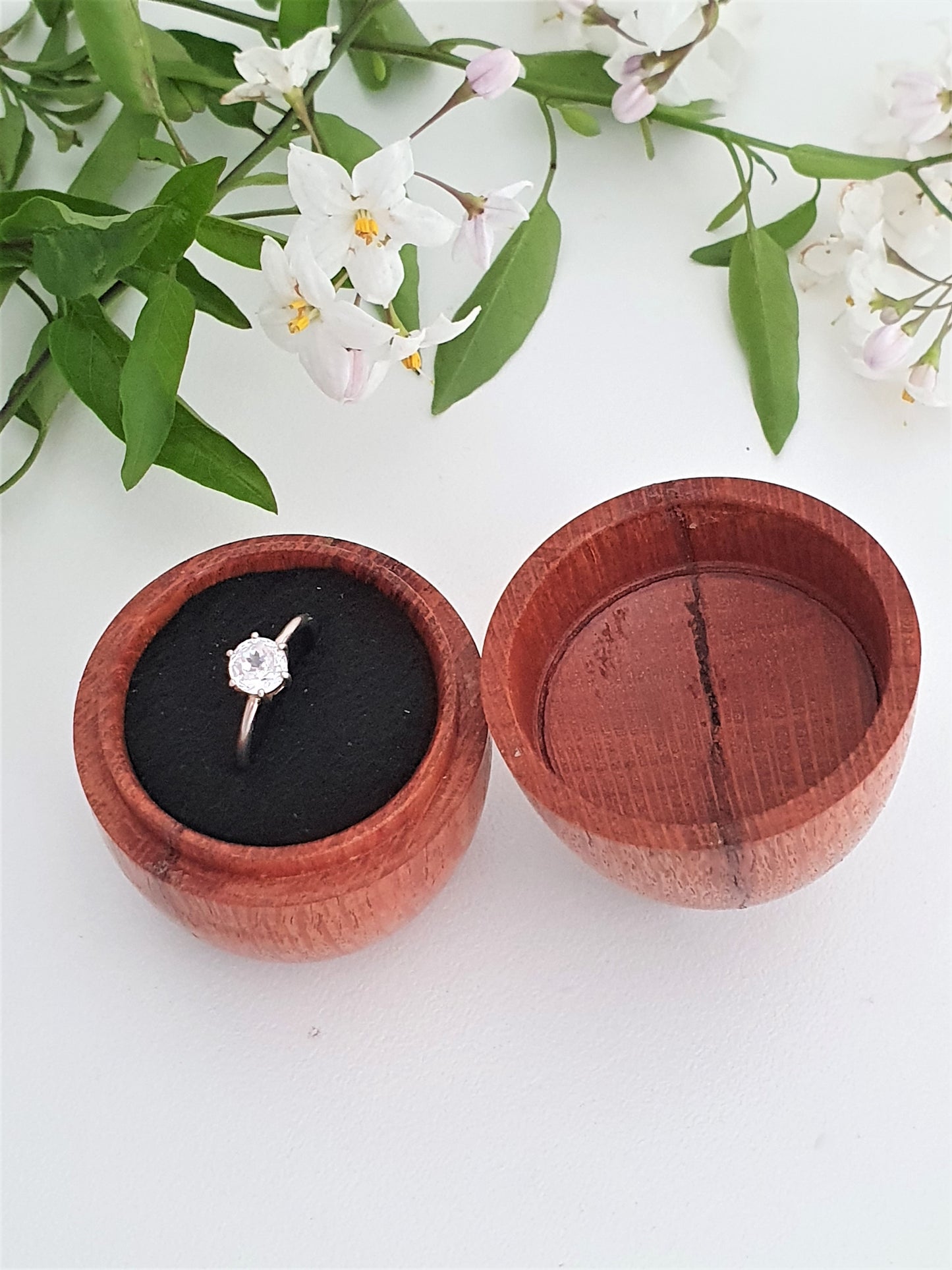 Wooden ring box with a diamond ring on a white background with flowers