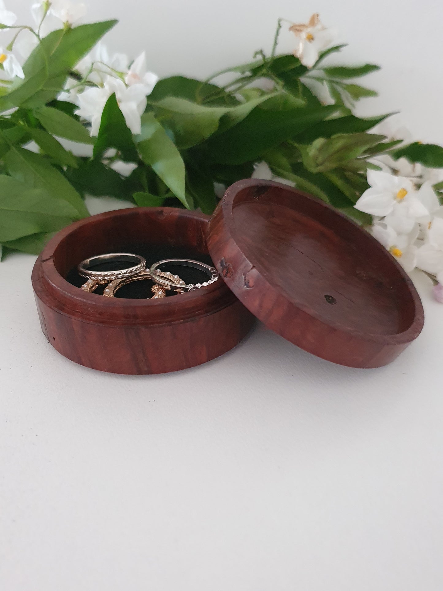 Wooden jewelry box with rings on a white background with greenery