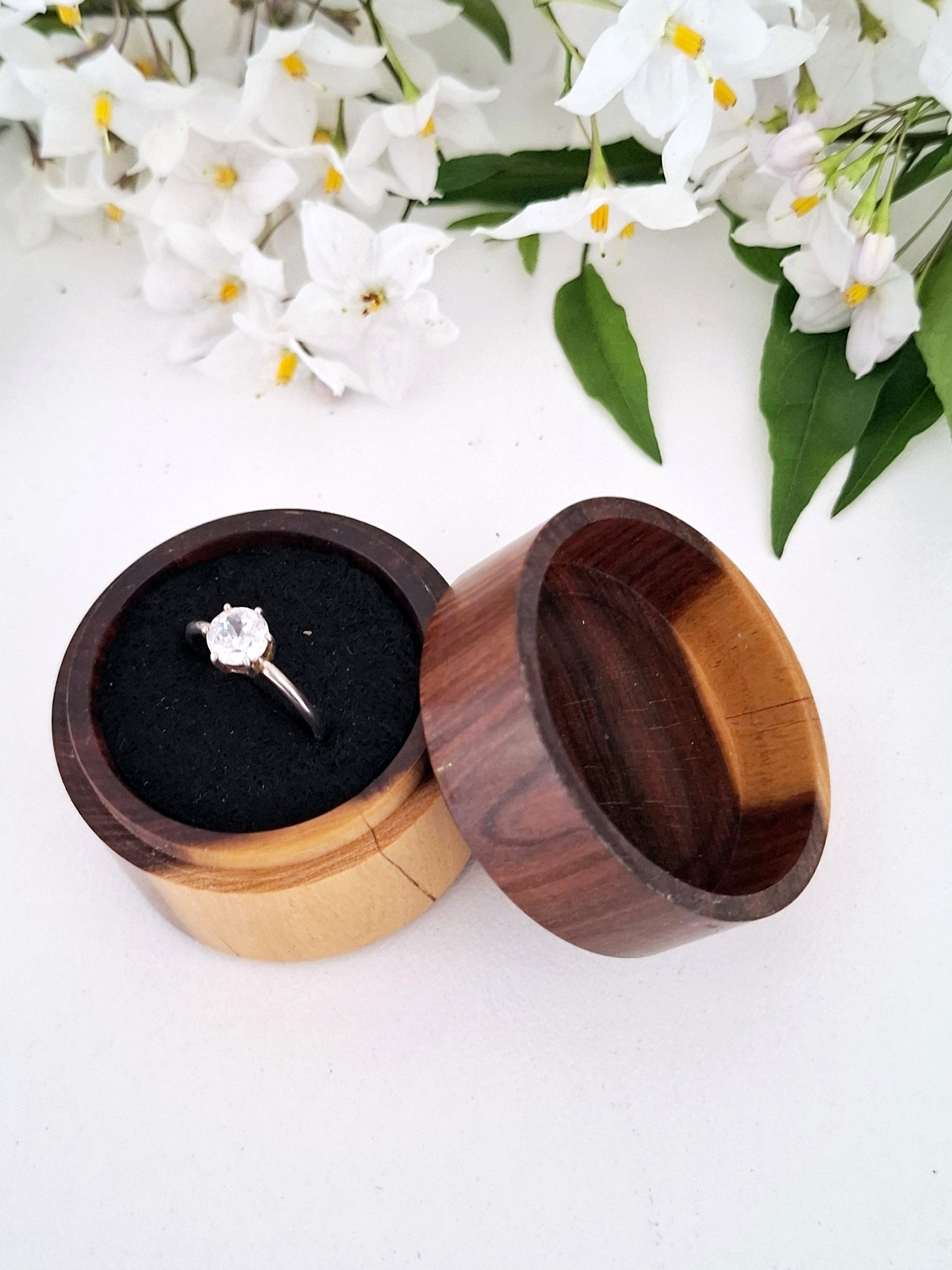 Wooden ring box with a diamond ring on a white background with flowers