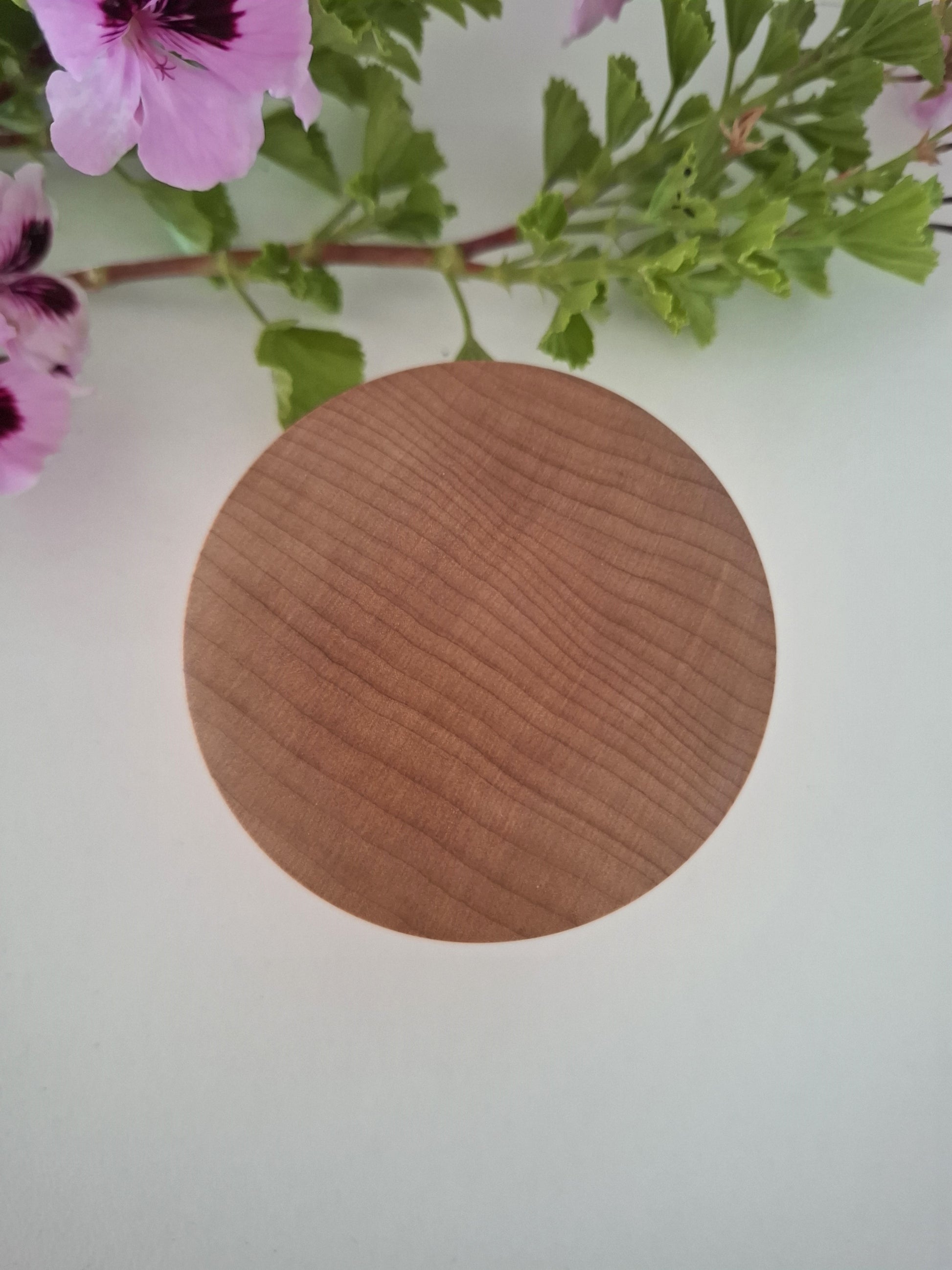 Wooden ring box with pink flowers and green leaves in the background